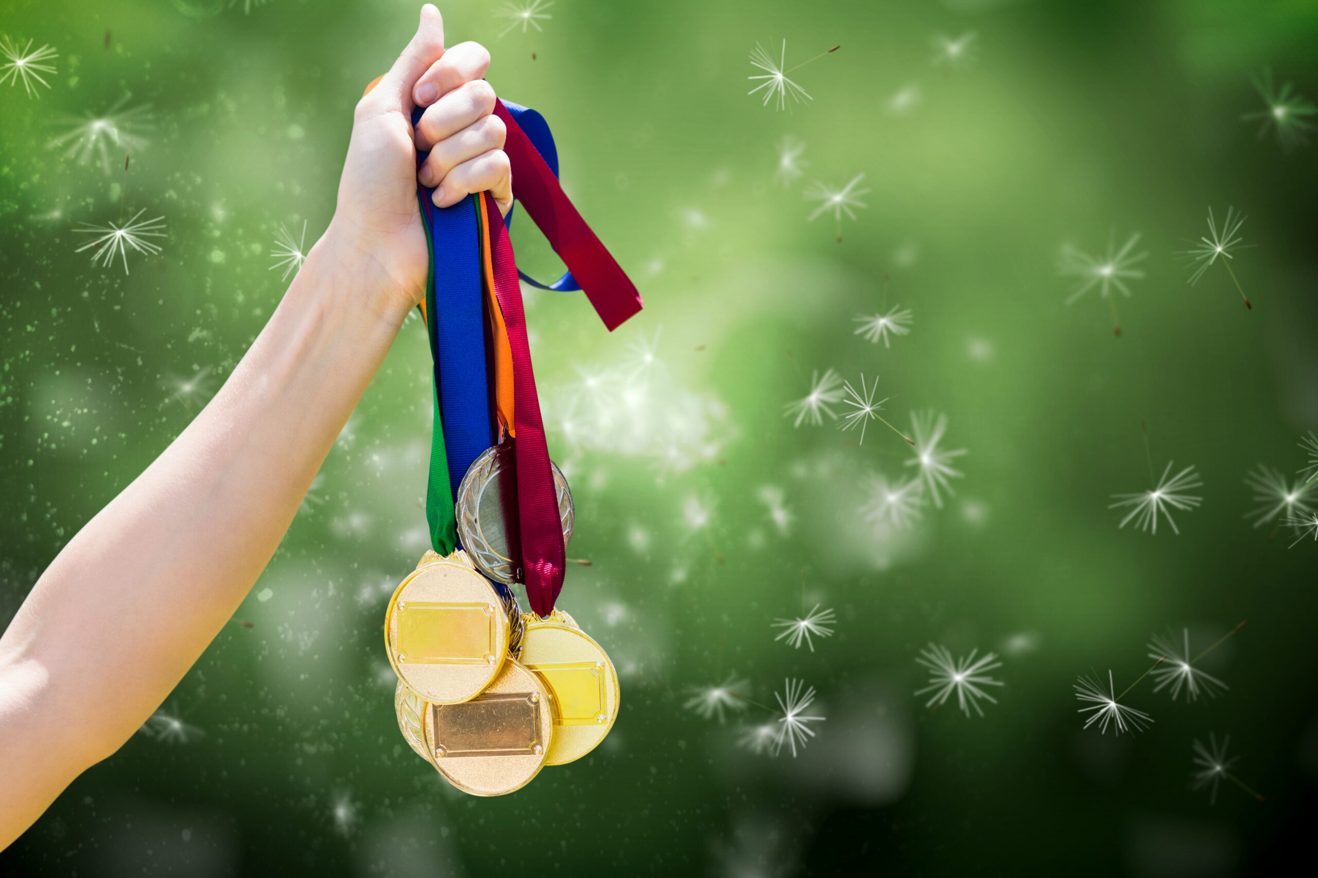 composite of hand holding medals over nature background